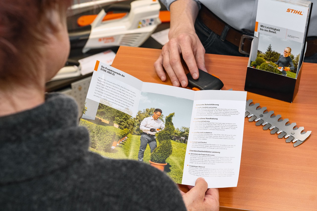 Людина дивиться на переваги STIHL HSA 25 у брошурі