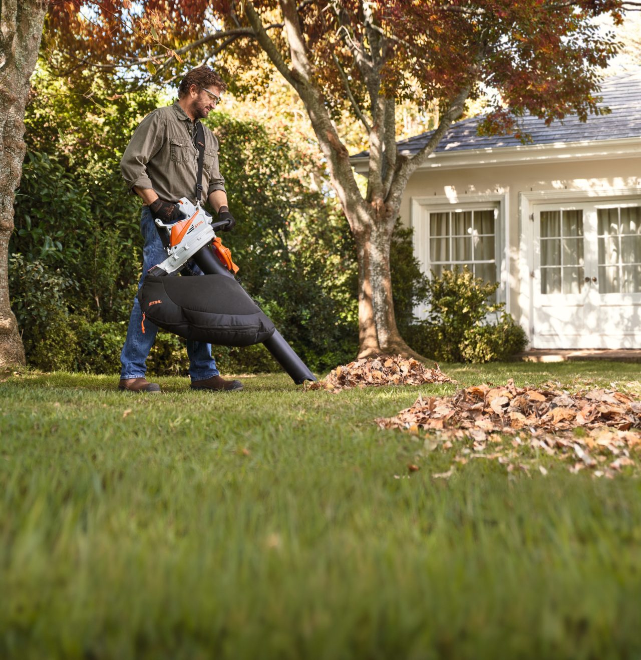 Чоловік збирає листя садовим пилососом STIHL