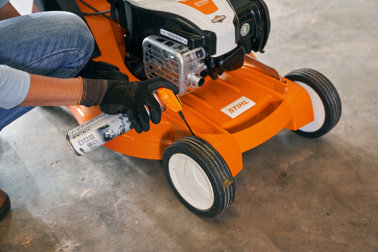 Жінка ставить бензинову газонокосарку STIHL RM 448 TC у гараж