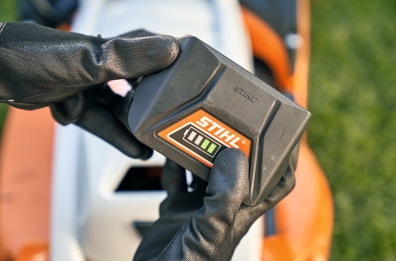 Літій-іонний акумулятор STIHL, на задньому плані акумуляторна газонокосарка STIHL RMA 339 C.