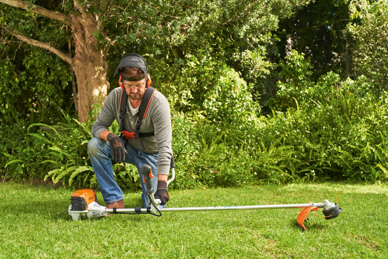 Чоловік кладе бензинову мотокосу STIHL FS 91 на землю для запуску
