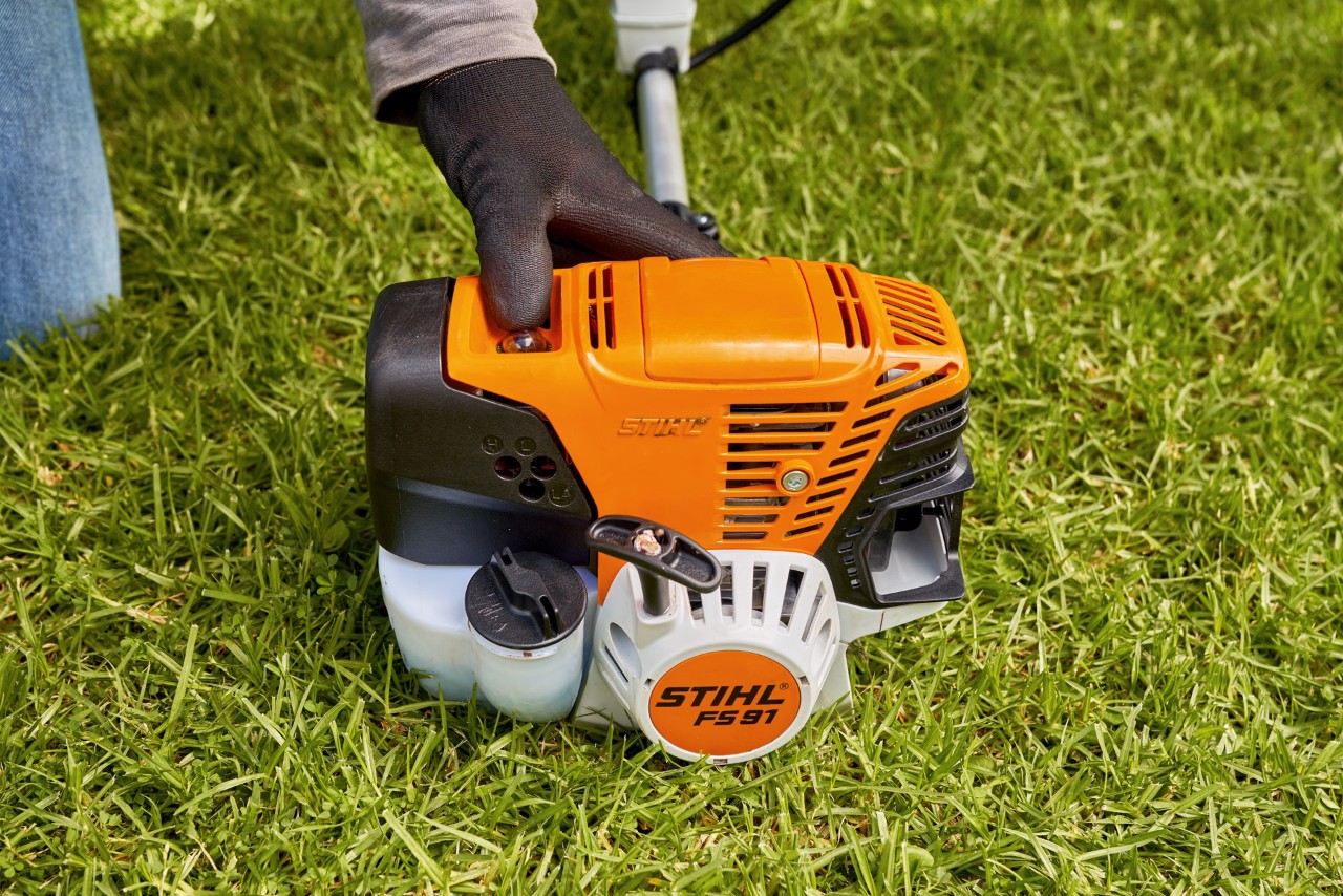 Чоловік натискає на паливний насос бензинової мотокоси STIHL FS 91, щоб запустити мотокосу
