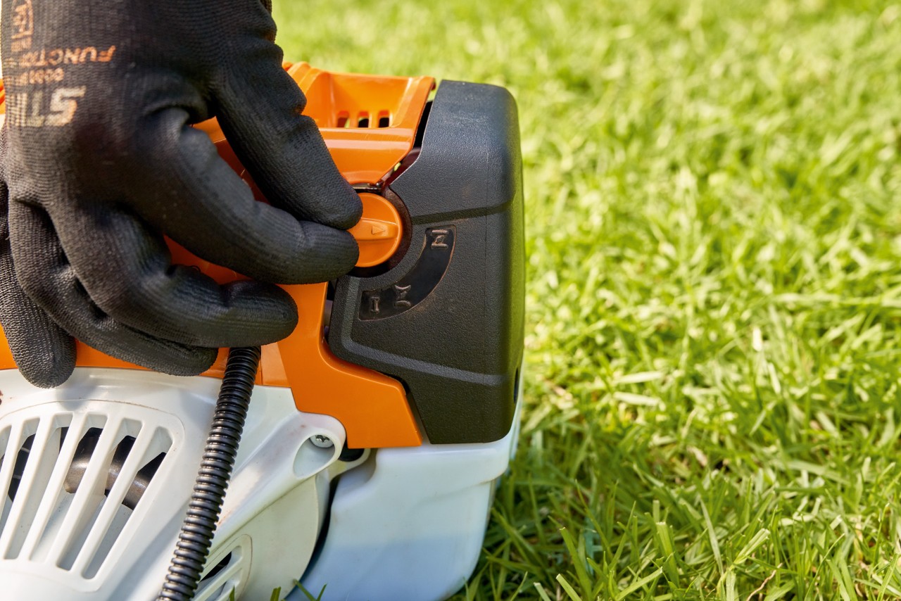 Чоловік регулює важіль паливного насоса бензинової мотокоси STIHL FS 91, щоб запустити мотокосу