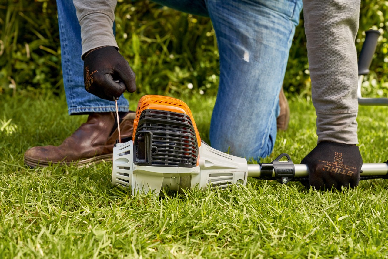 Чоловік тягне за мотузку стартера бензинової мотокоси STIHL FS 91