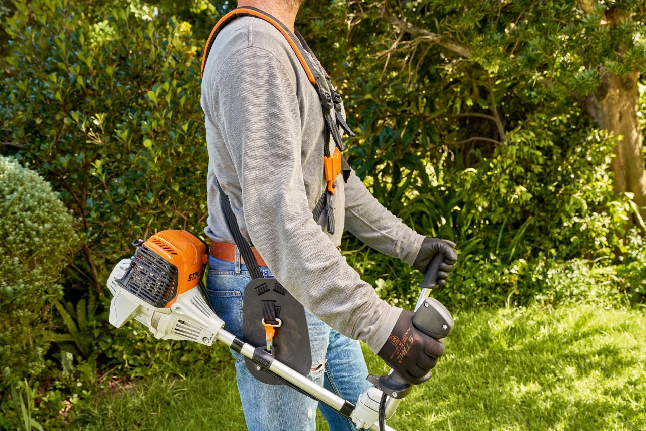 Чоловік піднімає з землі бензинову мотокосу STIHL FS 91, щоб почати косити