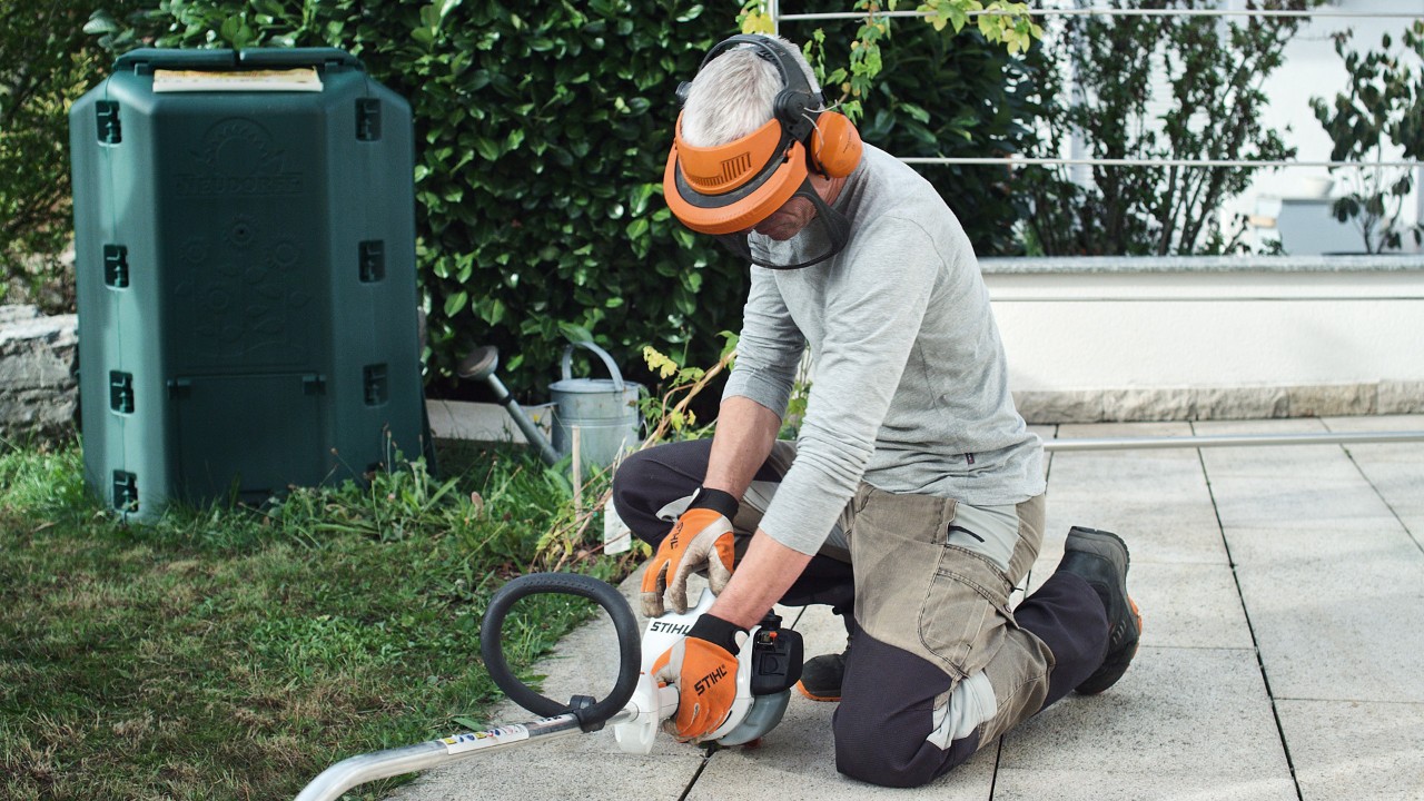 Чоловік в захисному одязі притискає до землі бензинову мотокосу STIHL FS 38
