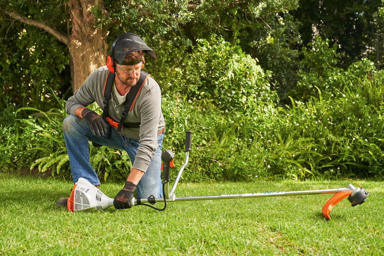 Чоловік кладе бензинову мотокосу STIHL FS 56 на землю для запуску