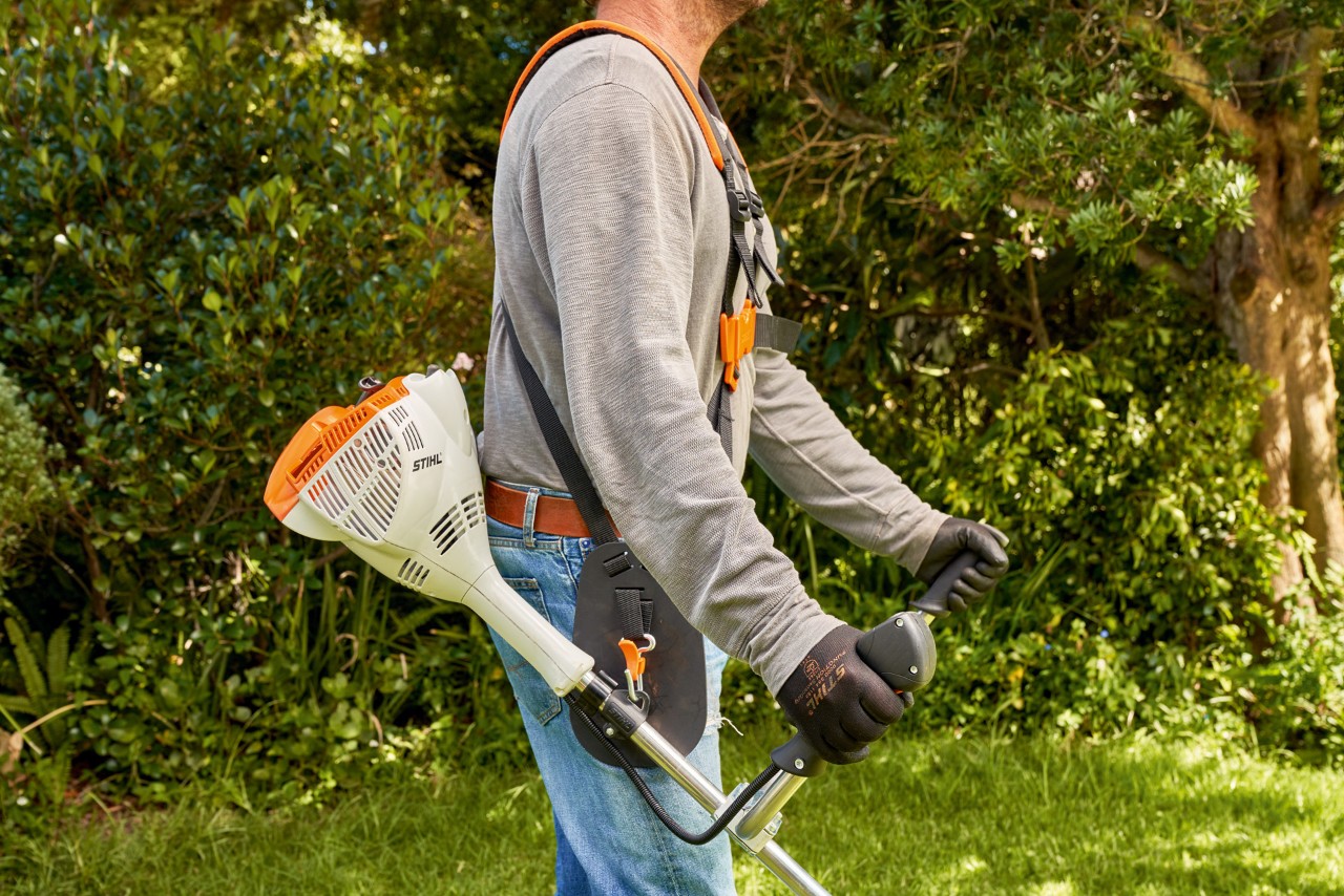 Чоловік піднімає з землі бензинову мотокосу STIHL FS 56