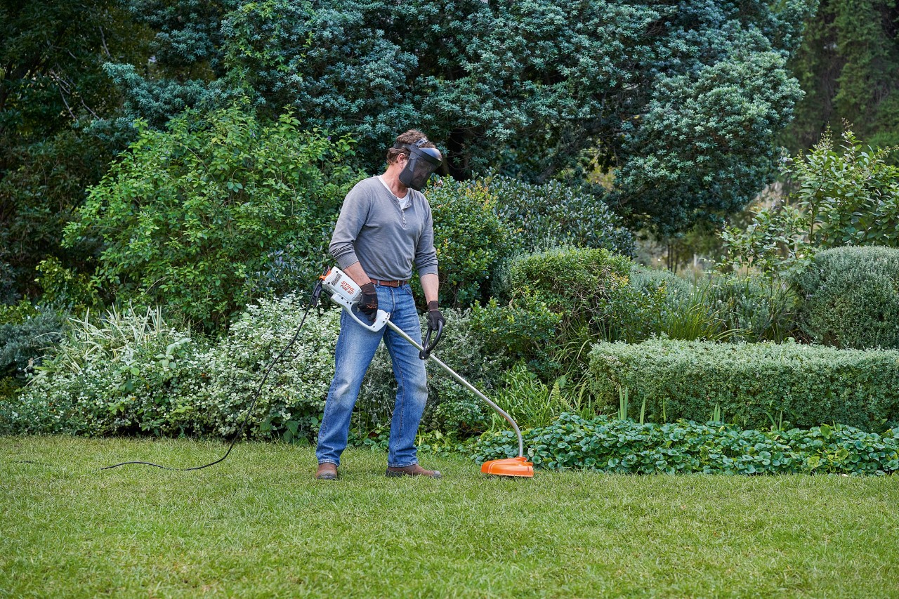 Чоловік з електричною мотокосою STIHL FSE 60 займає безпечне положення