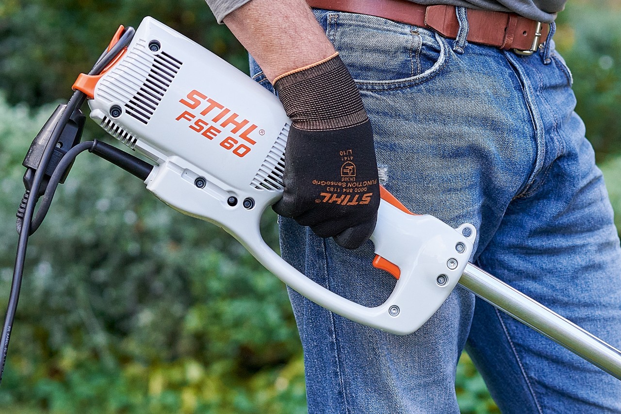 Чоловік натискає на вимикач, щоб вимкнути електричну мотокосу STIHL FSE 60.