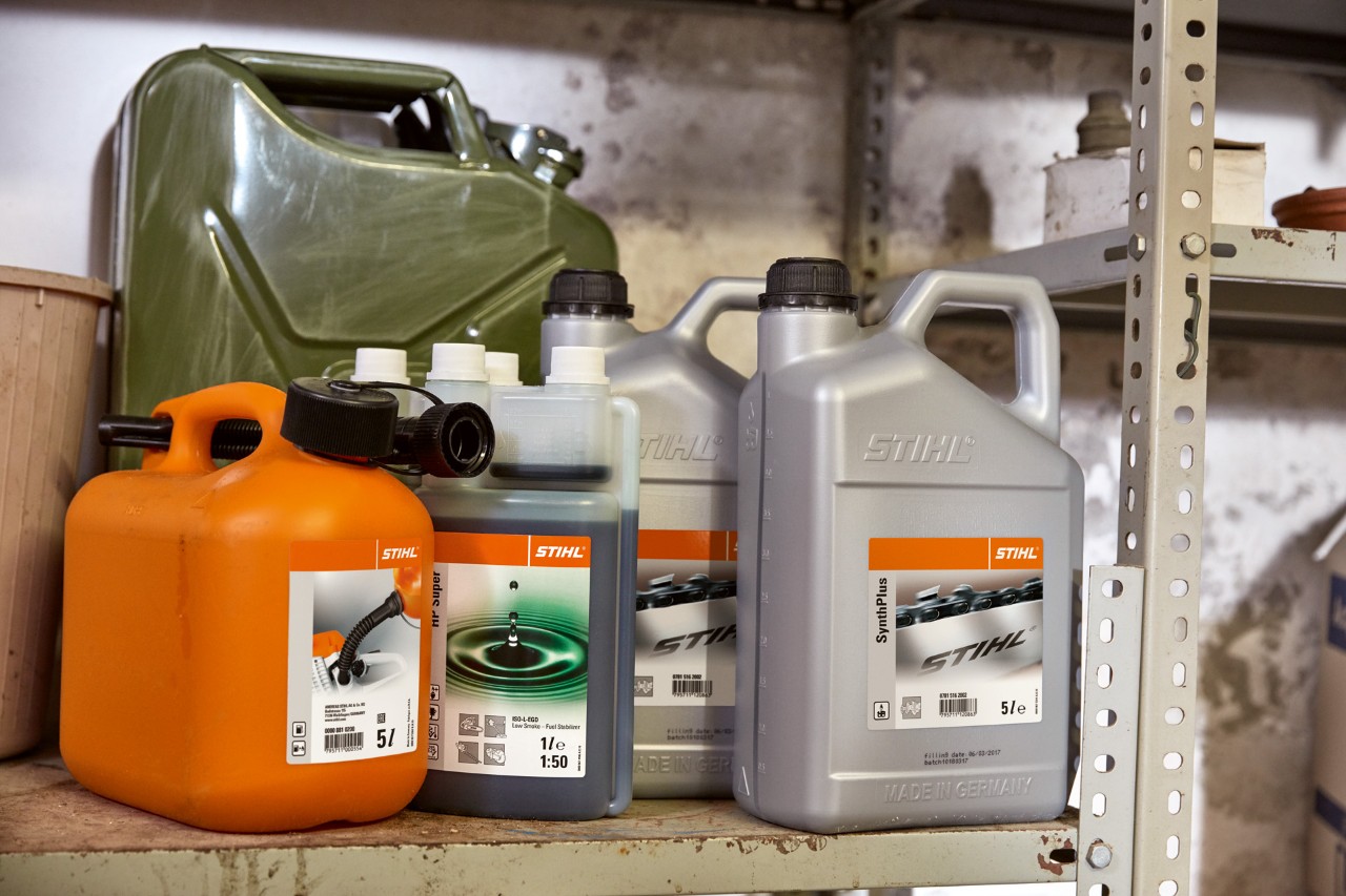 Каністра світлого кольору з мастилом STIHL HP Super і каністра помаранчевого кольору з сумішшю для мотокіс.