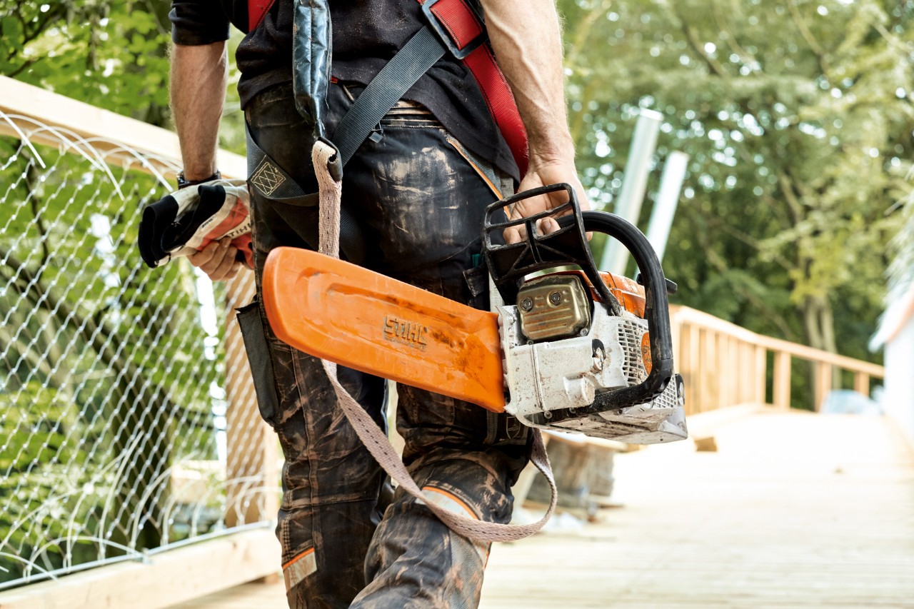 Чоловік у спецодязі тримає ланцюгову бензопилу STIHL MS 261 із захистом ланцюга.
