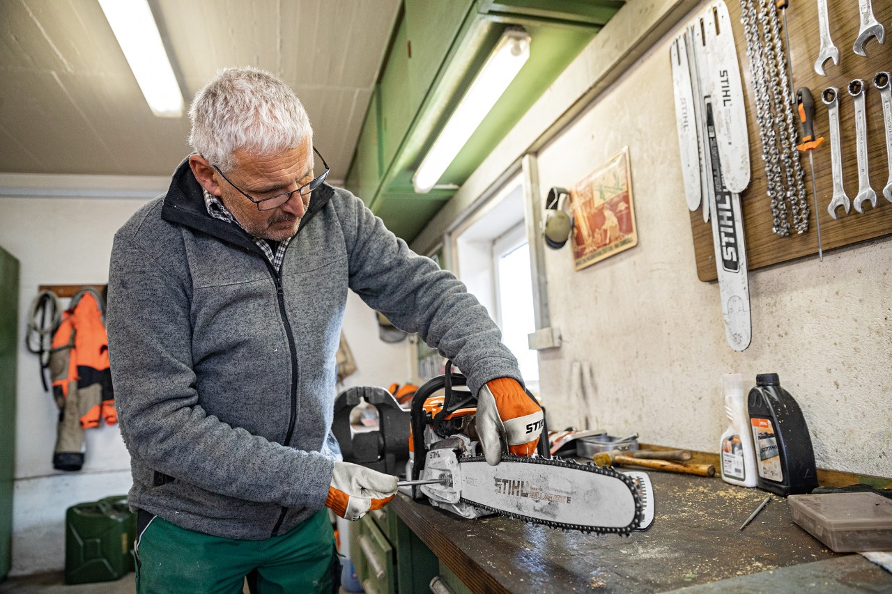 Чоловік затягує ланцюг ланцюгової пилки STIHL