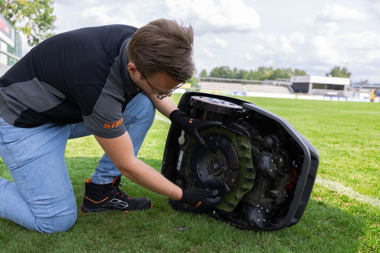 Газонокосарка-робот STIHL iMOW® нахилена на бік, готова до прибирання