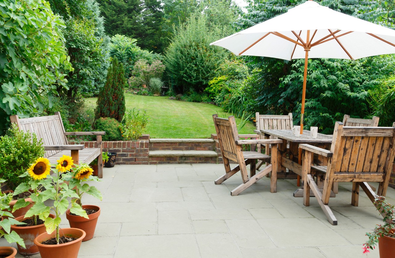 Geräumige Terrasse mit Betonsteinen an einem großen, grünen Garten