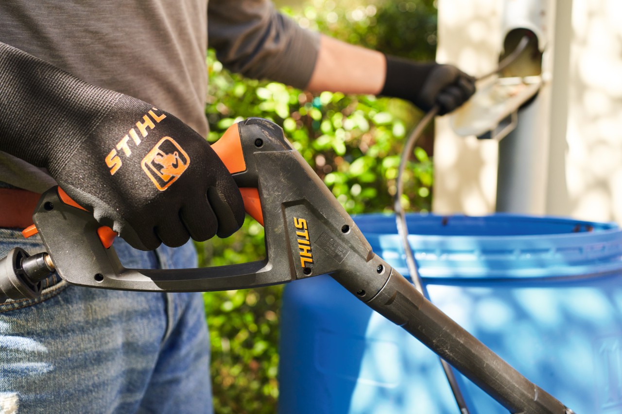 Person mit STIHL Hochdruckreiniger in der rechten Hand und Schlauch in der linken Hand, um sich bis zur Fallrohrverstopfung vorzutasten 