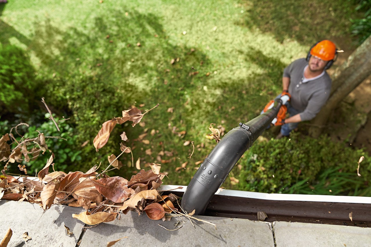 Чоловік чистить ринву за допомогою набору для чищення ринв STIHL