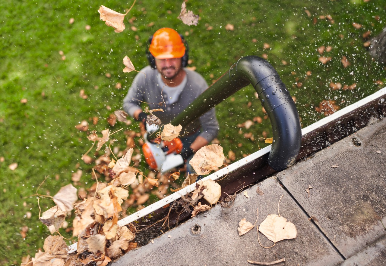 Mann reinigt Dachrinne mit STIHL Dachrinnenreinigungsset