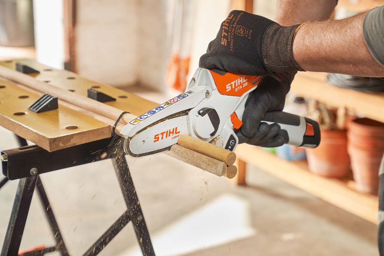 Ein Mann sägt Rundstäbe mit dem STIHL Akku-Gehölzschneider GTA 26
