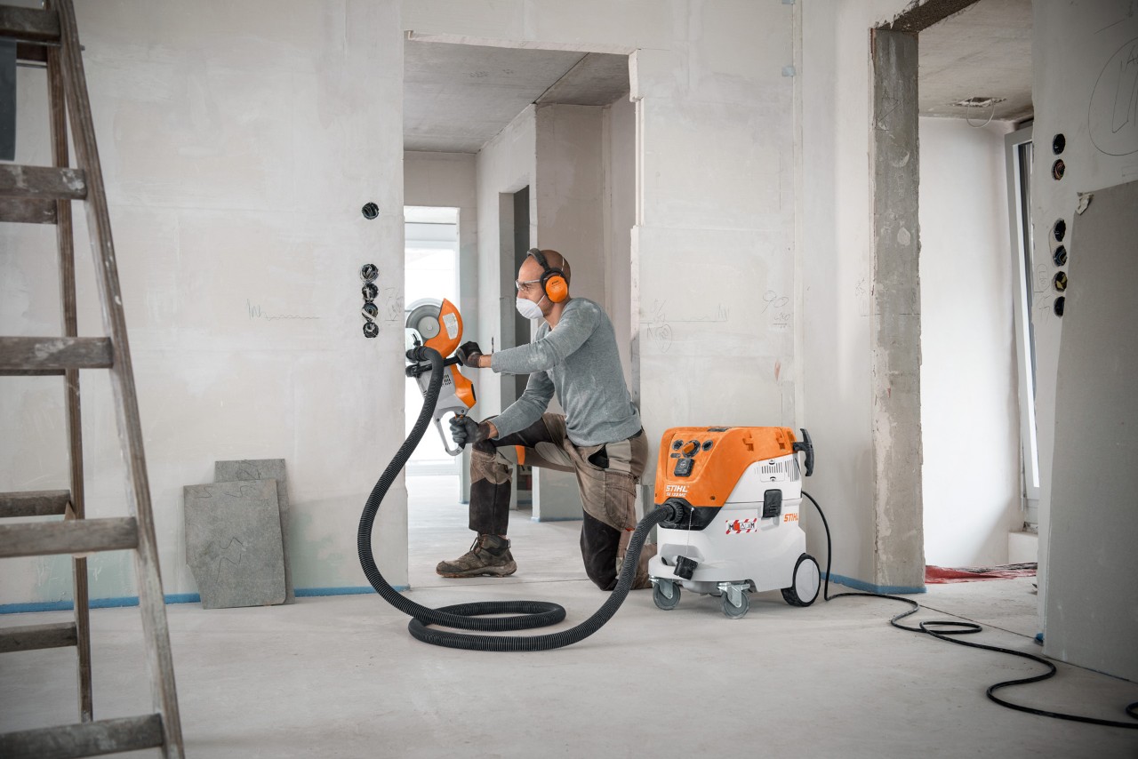 Чоловік використовує пилосос для вологого та сухого прибирання STIHL SE 133 ME під час роботи з моторізом STIHL TSA 230