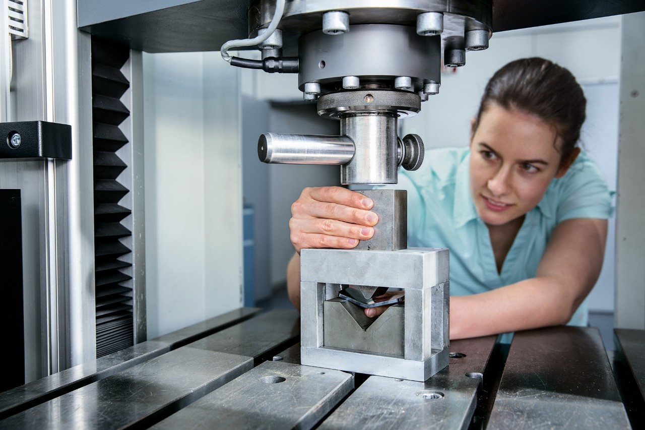 Frau bedient Hydraulikpresse für Biegeprüfung